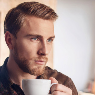 Nachdenklicher Mensch mit Teetasse in der Hand